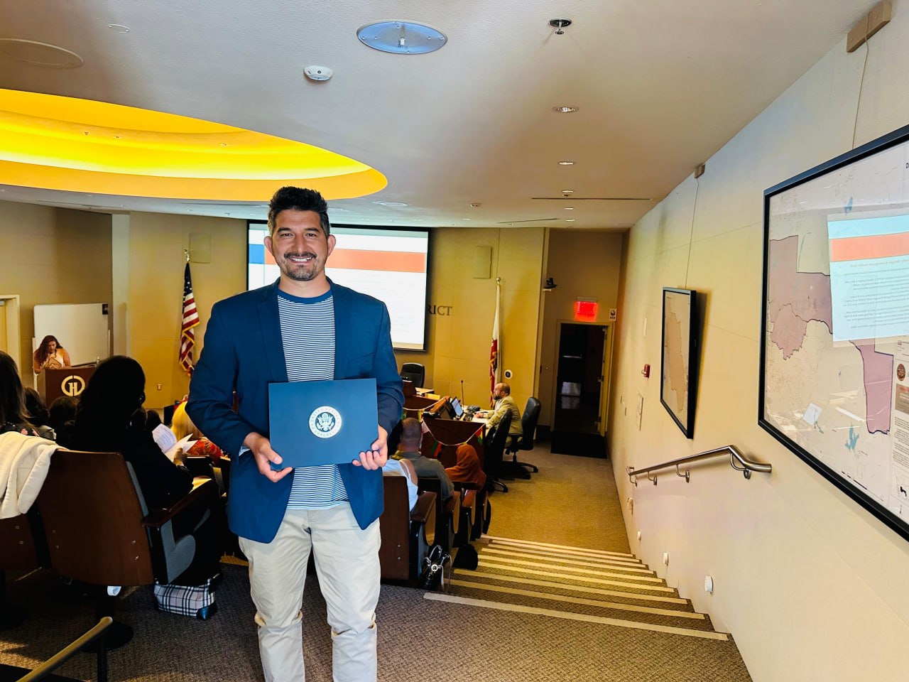 Mustafa Sharifi receiving a Certificate of Congressional Recognition at a podium