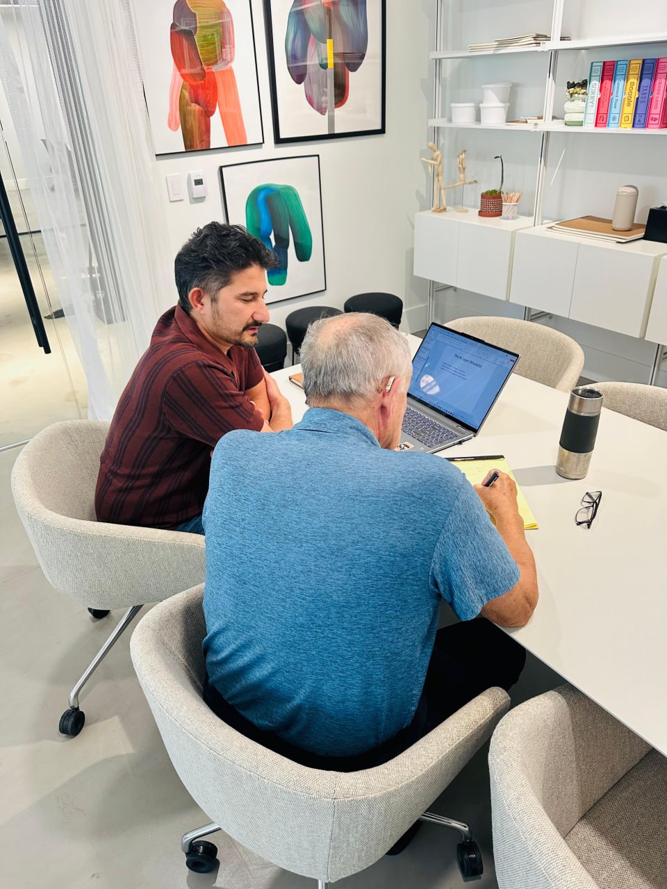 A real working session, Mustafa sitting next to a client at a laptop.